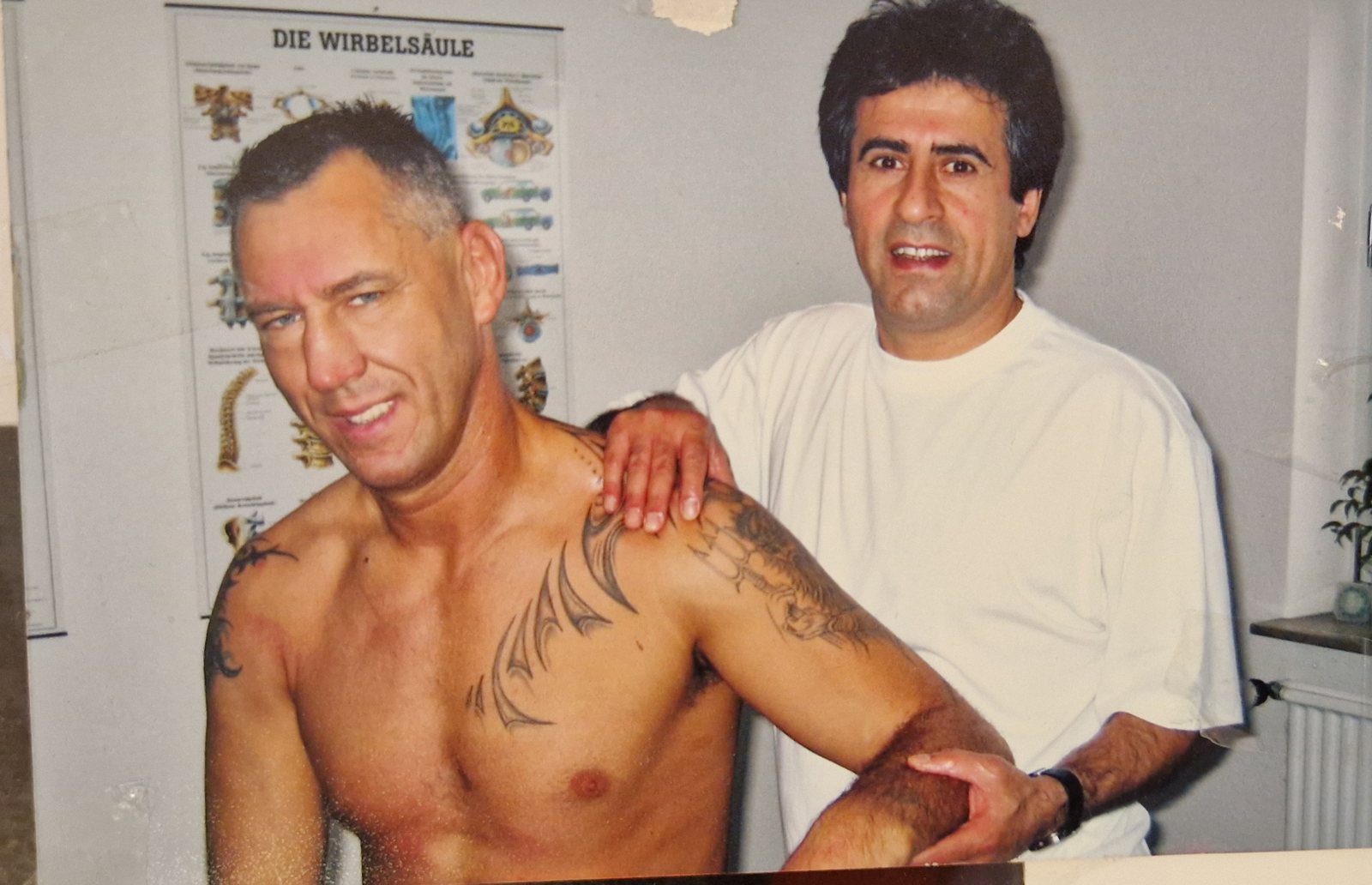 Jahan Golidj behandelt Boxweltmeister Andreas Sidon vor einer Anatomie-Tafel der Wirbelsäule